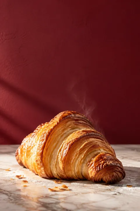 Croissant na marmurze na tle wiśniowej ściany